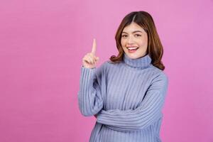 Porträt einer glücklichen jungen Frau, die mit dem Finger Nummer eins nach oben zeigt, isoliert über rosa Hintergrund foto