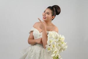 junge asiatische schöne Braut zeigt mit dem Finger glücklich auf weißem Hintergrund foto