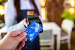 kontaktloses zahlungskonzept, frau, die kreditkarte in der nähe von nfc-technologie auf dem schalter hält, kunde macht transaktionszahlungsrechnung auf terminal-rfid-kassenmaschine im restaurantgeschäft, nahansicht foto