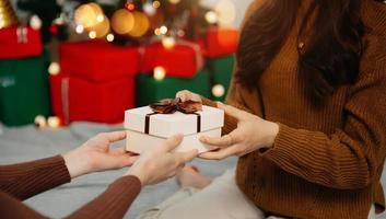 glückliche frau, die frau zu hause weihnachts- und neujahrsgeschenkbox gibt. familienweihnachtsfeier. Weihnachtsdekoration. foto