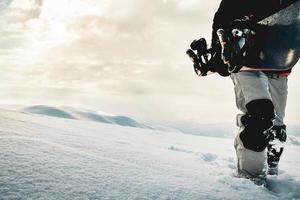 snowboarder in voller schutzausrüstung für extremes freeride-snowboarden, das mit einem snowboard-walking posiert. isoliert auf grauweißem Schneehintergrund. foto