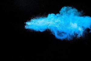 blaue pulverexplosionswolke auf schwarzem hintergrund. gestartete blaue staubpartikel spritzen. foto