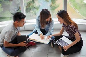 Studentengruppen sehen sich Informationen in Büchern und Laptops an. es gibt eine Geste der Zustimmung und ein Lächeln, froh, gemeinsam zu lernen. foto