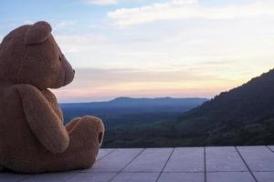 Teddybär sitzt allein auf einem Holzbalkon. traurig und einsam aussehen foto