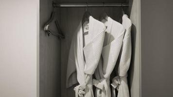 Drei Bademäntel hängen am Regal im Kleiderschrank im Hotelzimmer foto