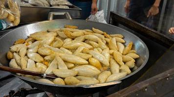 Gebratene Fischbällchen in Rugby-Form in einer Pfanne mit kochendem Öl mit traditionellem asiatischem Straßenessen im heißen Öl auf dem Markt in Thailand foto