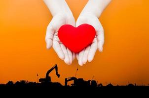 Schließen Sie herauf rotes Herz in den Händen der Frau, lokalisiert auf Industrieenergielandschaftshintergrund, Gesundheits-, Medizin-, Menschen- und Kardiologiekonzept, Energiekonzept foto