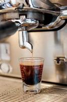 Closeup schwarzer Kaffee in Messbecher aufgesetzt Kaffeemaschine, Kaffeemaschine macht Espresso foto