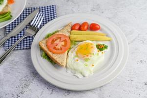 ein Spiegelei mit Toast, Karotten, Babymais und Frühlingszwiebeln foto