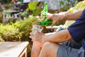 Mann, der im Urlaub Bier in Plastikglas aus der Flasche gießt. foto