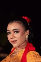 Scharfe Augen von indonesischen Frauen mit Make-up, während sie beim Tanzfestival ein orangefarbenes Kleid tragen foto