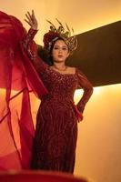 eine glamouröse frau posiert mit einem fliegenden roten kleid auf ihrem körper, während sie eine goldene krone trägt foto