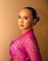 balinesische braut, die das rosa hochzeitskleid trägt, bevor die zeremonie begonnen hat foto