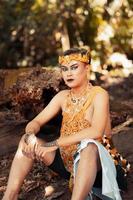 Balinesischer Mann sitzt im Wald und trägt eine goldene Krone in goldener Kleidung foto