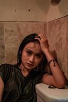 Heißes und nasses asiatisches Mädchen posiert mit sinnlichem Stil, während es schwarze nasse Kleider trägt foto
