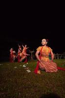 eine gruppe indonesischer tänzer, die auf der bühne mit einem roten schal und einem traditionellen orangefarbenen kleid innerhalb des festivals auftreten foto