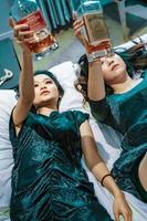 asiatische frauen, die im schlafzimmer eine alkoholflasche in der hand halten foto