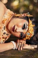 balinesische Frau mit goldener Krone und goldener Halskette, die auf dem Felsen schläft foto