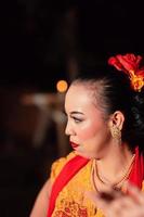 Schöne asiatische Frau mit Make-up und Blumenaccessoires auf ihrem Haar, während sie Goldschmuck trägt foto