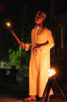 ein muslimischer mann, der mit der feuerfackel in der hand vor dem dorf steht foto