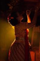 balinesische frauen, die kulturelle kleidung tragen, während sie mit tänzerischen bewegungen vor der beleuchtung posieren foto
