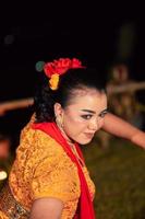 Schönes Gesicht einer indonesischen Frau im Make-up, während sie während des Festivals einen traditionellen Tanz in einem orangefarbenen Kostüm tanzt foto