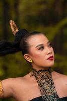 Wunderschöne asiatische Frau im Make-up mit schwarzen Haaren und rotem Lippenstift, die während der Tanzaufführung goldenen Schmuck trägt foto