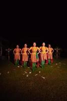 balinesische tänzer, die zusammen mit rotem schal und orangefarbenen kostümen auf der bühne stehen, nachdem sie den traditionellen tanz aufgeführt haben foto