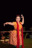 Sundanesin mit exotischem Gesicht, die während einer Tanzausstellung ein gelbes Kleid und einen roten Schal trägt foto