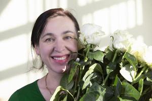 glückliche Frau mittleren Alters mit Rosenstrauß lächelnd und mit Blick auf die Kamera. Frau fünfzig Jahre alt. foto