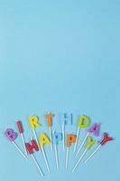 bunte Kerzen in Buchstaben mit Happy Birthday-Schriftzug isoliert auf blauem Hintergrund foto