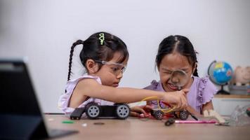 asiatische schüler lernen zu hause, indem sie roboterautos und elektronische platinenkabel in stamm, dampf, mathematik, ingenieurwesen, wissenschaft, technologie, computercode in robotik für kinderkonzepte codieren. foto