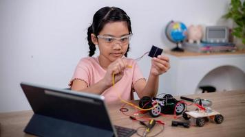 asiatische schüler lernen zu hause, indem sie roboterautos und elektronische platinenkabel in stamm, dampf, mathematik, ingenieurwesen, wissenschaft, technologie, computercode in robotik für kinderkonzepte codieren. foto