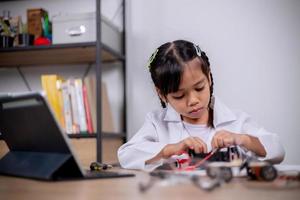 asiatische schüler lernen zu hause, indem sie roboterautos und elektronische platinenkabel in stamm, dampf, mathematik, ingenieurwesen, wissenschaft, technologie, computercode in robotik für kinderkonzepte codieren. foto