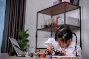 asiatische schüler lernen zu hause, indem sie roboterautos und elektronische platinenkabel in stamm, dampf, mathematik, ingenieurwesen, wissenschaft, technologie, computercode in robotik für kinderkonzepte codieren. foto