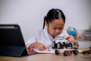 asiatische schüler lernen zu hause, indem sie roboterautos und elektronische platinenkabel in stamm, dampf, mathematik, ingenieurwesen, wissenschaft, technologie, computercode in robotik für kinderkonzepte codieren. foto