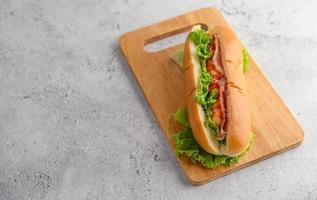 großer Hotdog mit Salat auf Holzschneidebrett foto