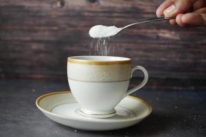 weißen Zucker in eine Kaffeetasse gießen, foto