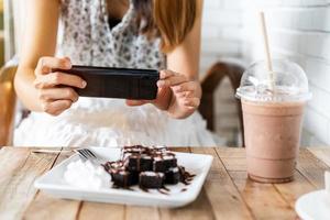 junge Frau, die auf Reisen mit dem Smartphone im Restaurant ein Foto von Lebensmitteln macht