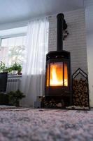Schwarzer Ofen, Kamin im Inneren des Hauses im Loft-Stil. alternative umweltfreundliche heizung, warmes gemütliches zimmer zu hause, verbrennung von holz foto