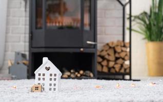 Schlüssel zum Haus mit Schlüsselanhänger vor dem Hintergrund des Kaminofens mit Feuer und Brennholz. gemütlicher Herd zu Hause. Bau, Design, Projekt, Umzug in ein neues Haus, Hypothek, Miete und Kauf von Immobilien foto