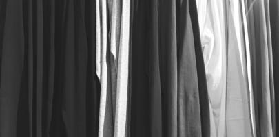 kunstmuster aus kleidung, baumwolle oder stoff, die im modegeschäft im schwarz-weiß-stil für den hintergrund in einer schlange hängen foto