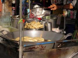 bangkok, thailand - 30. januar 2023 mann, der heiße gebratene fischbällchen oder fleischbällchen auf dem straßenlebensmittelmarkt auf dem chatuchak-markt, bangkok, thailand, kocht. thailändisches lokales Essen und Foto des Straßenlebens.