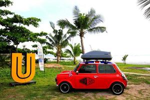 bangkok, thailand - 29. januar 2023 roter mini austin classic car mit schwarzem rad und grauer dachbox parkplatz am strand mit kokospalme und meer. transport- und oldtimerkonzept foto