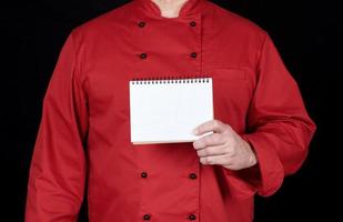Koch in roter Uniform mit einem leeren Notizbuch foto