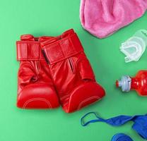 rote Boxhandschuhe aus Leder, eine Plastikwasserflasche und ein rosa Handtuch foto