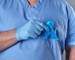 Arzt in Uniform und Latexhandschuhen, der ein blaues Band in der Hand hält foto