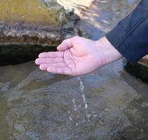 männliche Palme schöpft Wasser aus einer natürlichen Quelle foto