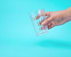 die hand der frau, die ein leeres transparentes glas hält foto