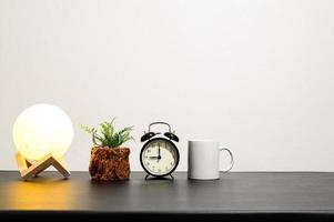 Lampe mit Pflanze, Uhr und Becher foto